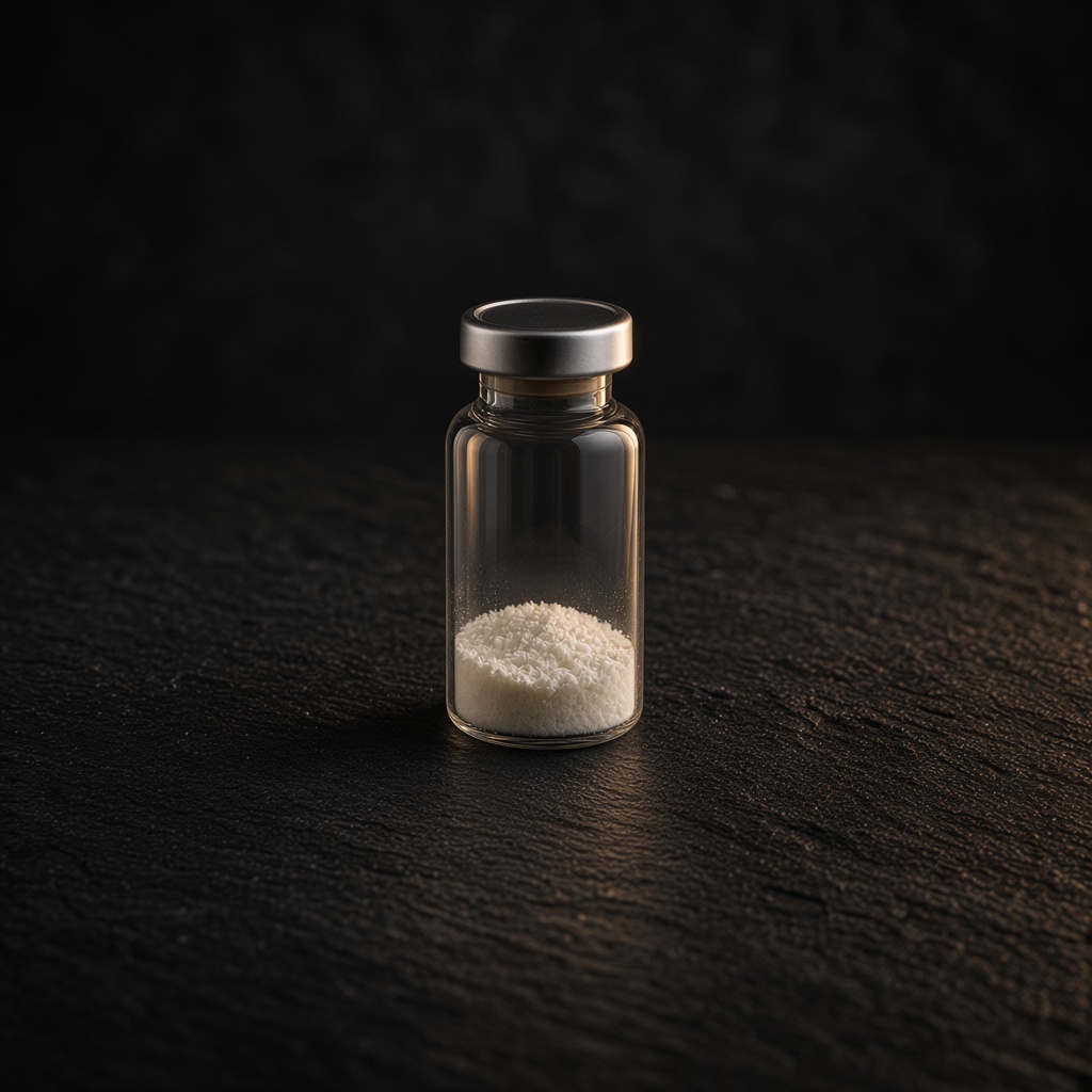 Clear glass research vial with a champagne neck band, set back on dark stone.